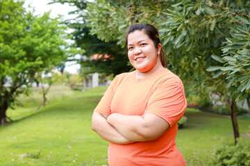 Portrait of a fat Asian woman exercising outdoors on the lawn. She smiles happily. Sports concept,...