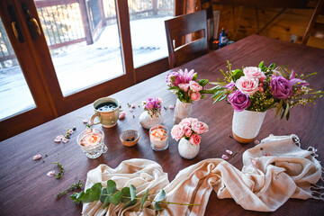 top view of a collection of white vases with pink and purple roses with candles and a white linen cloth - spa, spring and bridal vibes