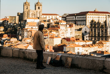 Painter admiring the Cathedral and houses of Porto from the viewpoint at sunset. Porto, Portugal