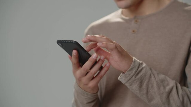 Cropped view of man using smartphone.Man taps and scrolls with finger on smartphone screen.
