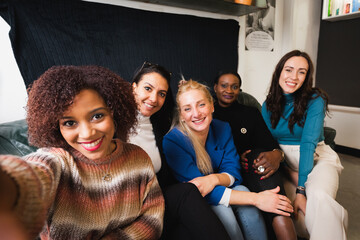 group of casual females with different ethnicity take selfie in sofa.