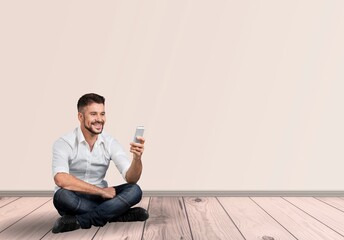 Happy young smart man posing with phone on background