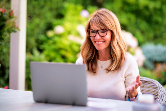 Cheerful smiling mid aged woman using laptop for work