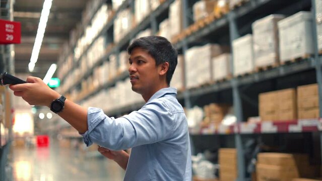Man worker checking products with barcode scanner in warehouse.