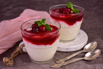 Rice pudding with cherry jam on a gray background.
