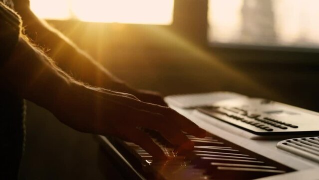 playing the piano synthesizer, close-up hands and sun glare. The concept of learning music.