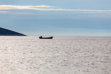 Obraz premium Barca de pesca en medio del mar en clama al atardecer