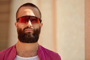 Portrait of a man with a beard, wearing glasses, a professional athlete cyclist on the background of the park.