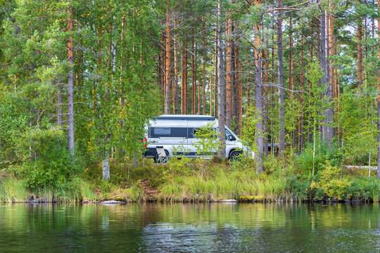 Wohnmobil an einem See im Wald, Blick vom Wasser aus, Campervan Stellplatz