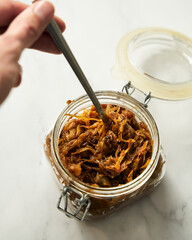 Homemade Caramelized onions in the jar. Man's Hand with spoon reaches into the jar