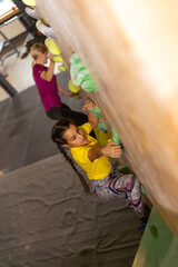 Obraz premium Young female bouldering instructor helping boy climb artificial wall