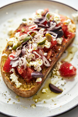 Dakos salad traditional Greek salad with soaked and crunchy barley rusks or bread, topped with juicy tomatoes, feta cheese, onions, olives, and a drizzle of olive oil. Popular apetizer