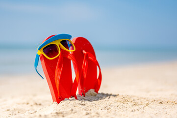 Women yellow sunglasses and red flip-flops on sandy. Travel by sea. Beach vacation.tropical sandy beach, summer travel, vacation and  summer holiday concepts.