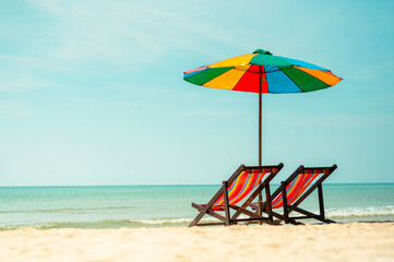 Two colorful deck chair and colorful an umbrella.tropical sandy beach, summer travel, vacation and summer holiday concepts.