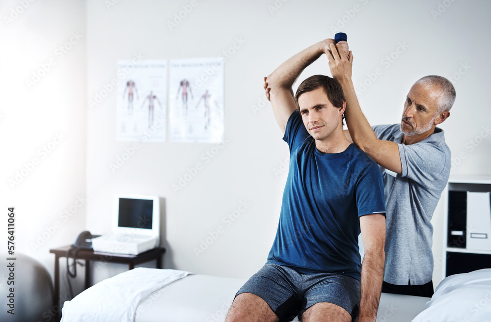 Poster working on improving his mobility. shot of a physiotherapist helping a patient work through his reco