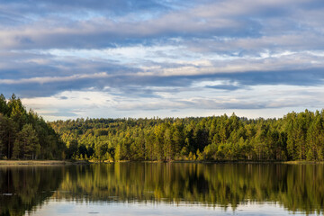 Fototapeta na wymiar spiegelglatter Waldsee mit schönem Himmel, Nadelwald