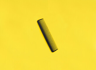 One black hair comb on the yellow background. Copy space. Top view.