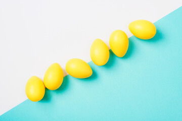 Yellow Easter eggs on white and blue background. Top view, flat lay, copy space