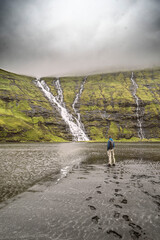 Ein einsamer Wanderer bewundert den Wasserfall der in die Bucht bei Saksun mündet. Die Färör...