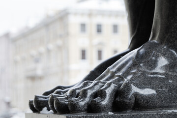 Toes of black granite Atlas statue. Classic architecture