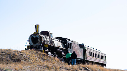 Old rusty, abandoned steam locomotive and train carriage. Abandoned railroad tracks in the desert.