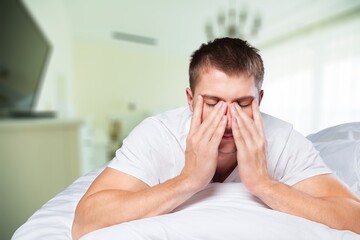 Sleep deprived young man in bed at home.