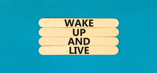 Wake up and live symbol. Concept words Wake up and live on wooden stick. Beautiful blue table blue...