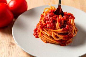 Macro view of a spaghetti nest with tomato sauce and a fork over a wooden table