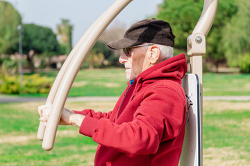 Lateral half body view of an old man using a chest press in a park