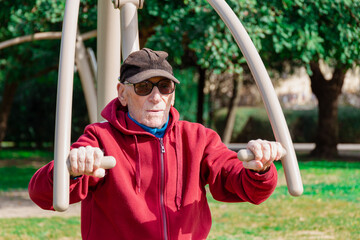 Half body view of an old man using a chest press in a park