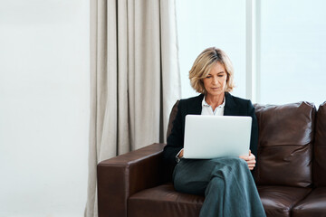 Keep up to date on the latest trends in psychotherapy. Shot of a mature psychologist sitting on a sofa and using a laptop.