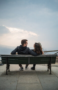 couple sitting on bench, looking to each other