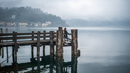 Woman standing on the pier, foggy weather, Lake Orta (Italy)