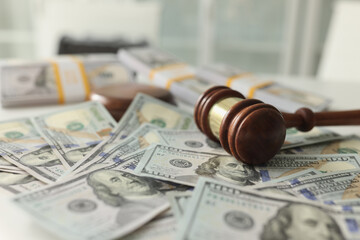 Wooden judge gavel and pile of dollars on table