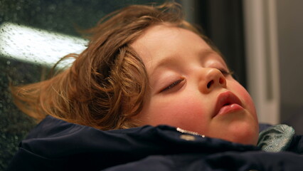 Candid child sleeping in train. Closeup small boy asleep on mother lap while traveling. Kid napping