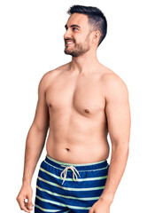 Fototapeta premium Young handsome man wearing swimwear looking away to side with smile on face, natural expression. laughing confident.
