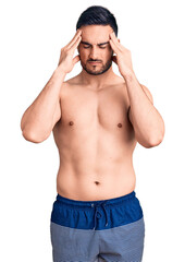 Fototapeta premium Young handsome man wearing swimwear suffering from headache desperate and stressed because pain and migraine. hands on head.