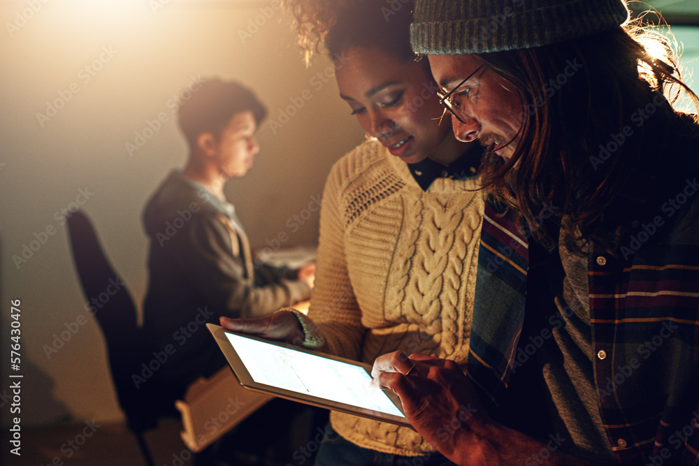 Poster Doing whatever it takes to get the job done. Shot of two coworker discussing something on a digital tablet while working night shift at the office.