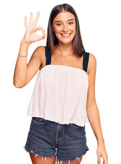 Obraz premium Young hispanic woman wearing casual clothes smiling positive doing ok sign with hand and fingers. successful expression.