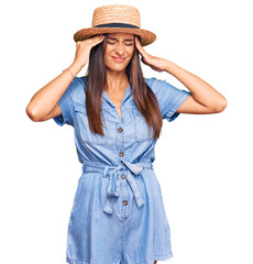 Young hispanic woman wearing summer hat suffering from headache desperate and stressed because pain and migraine. hands on head.