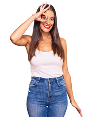 Fototapeta premium Young hispanic woman wearing casual clothes smiling happy doing ok sign with hand on eye looking through fingers