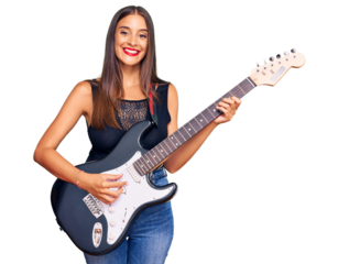 Young hispanic woman playing electric guitar looking positive and happy standing and smiling with a confident smile showing teeth