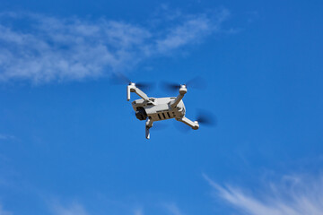 A small drone flies in the air against a blue sky