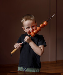 boy eats sausages on a skewer