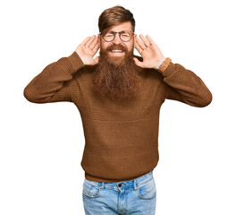 Fototapeta premium Young irish redhead man wearing casual clothes and glasses trying to hear both hands on ear gesture, curious for gossip. hearing problem, deaf