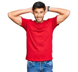 Young handsome man wearing casual red tshirt relaxing and stretching, arms and hands behind head and neck smiling happy