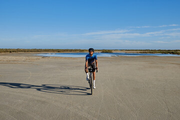 A cyclist is climbing up a mountain road on a gravel bike.A male cyclist is cycling in the...