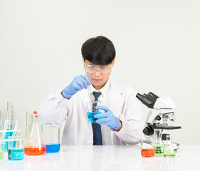 Asian male student scientist Wearing a doctor's gown in the lab looking at the chemist. caused by...