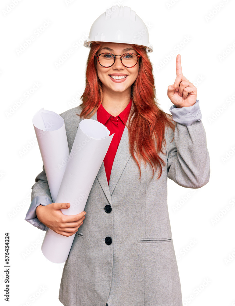 Wall mural young redhead architect woman wearing safety helmet holding blueprints surprised with an idea or que