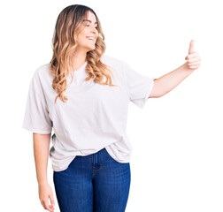 Young caucasian woman wearing casual clothes looking proud, smiling doing thumbs up gesture to the side